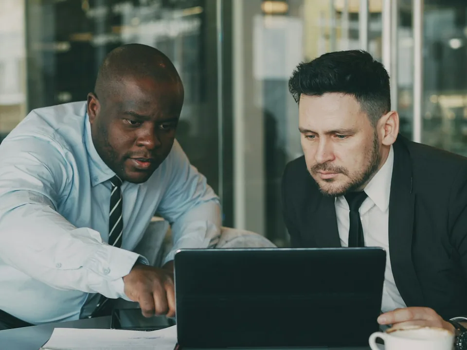 Two investors reviewing a business plan on a laptop