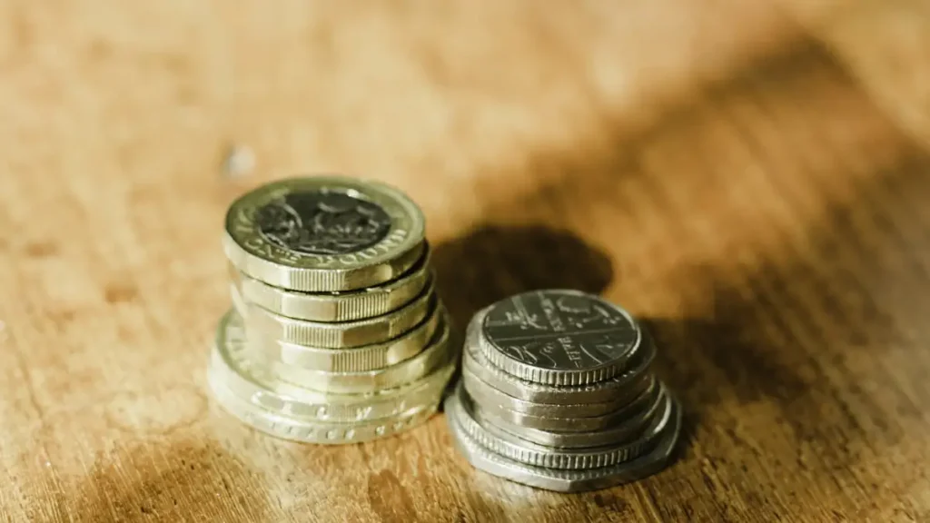 Pound sterling coins stacked on a wooden desk, illustrating Bali visa costs converted into GBP