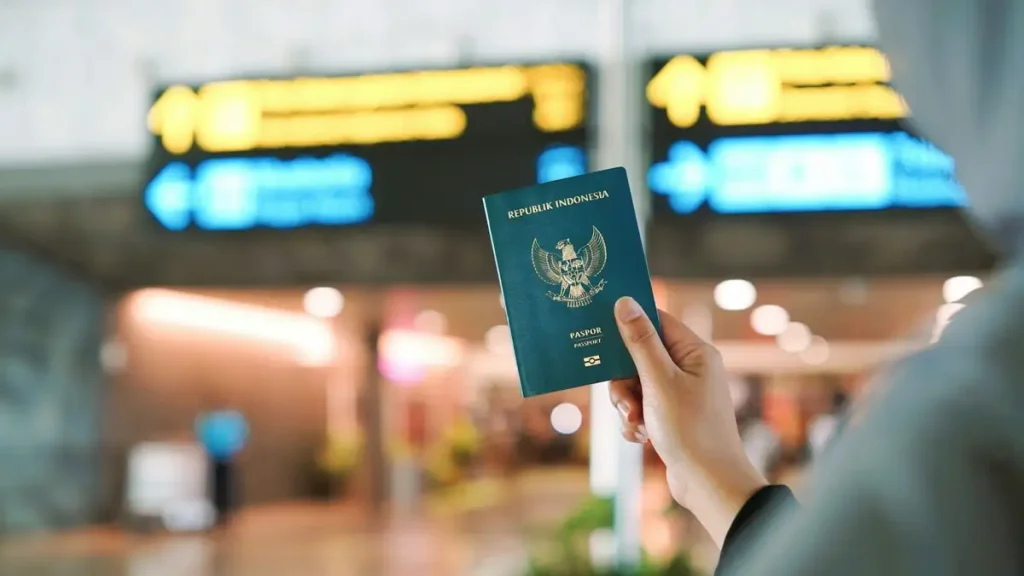 A traveller holding an Indonesian passport in an airport terminal after visa approval