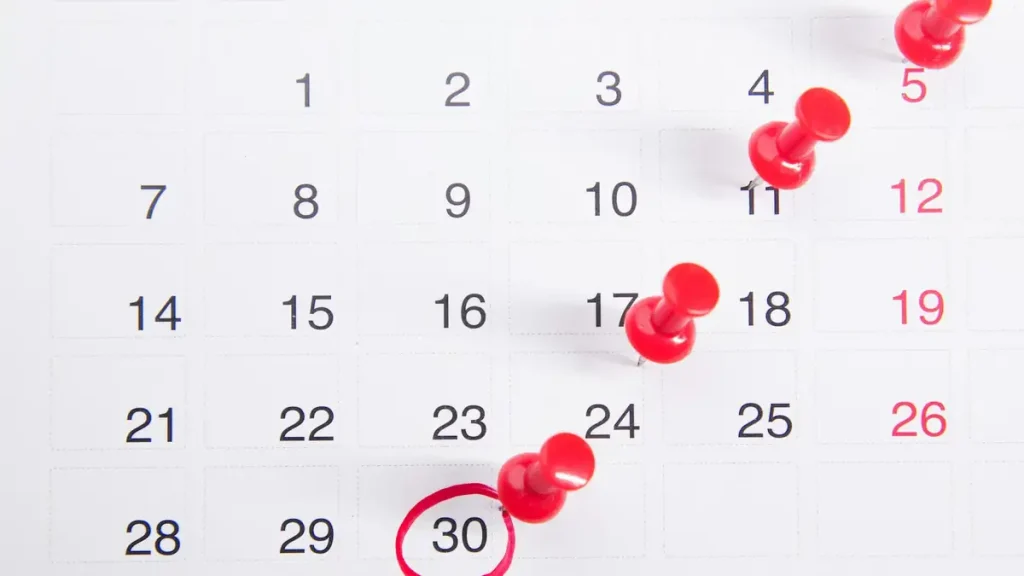 A wall calendar with red pins marking dates, used to plan Bali visa application timing
