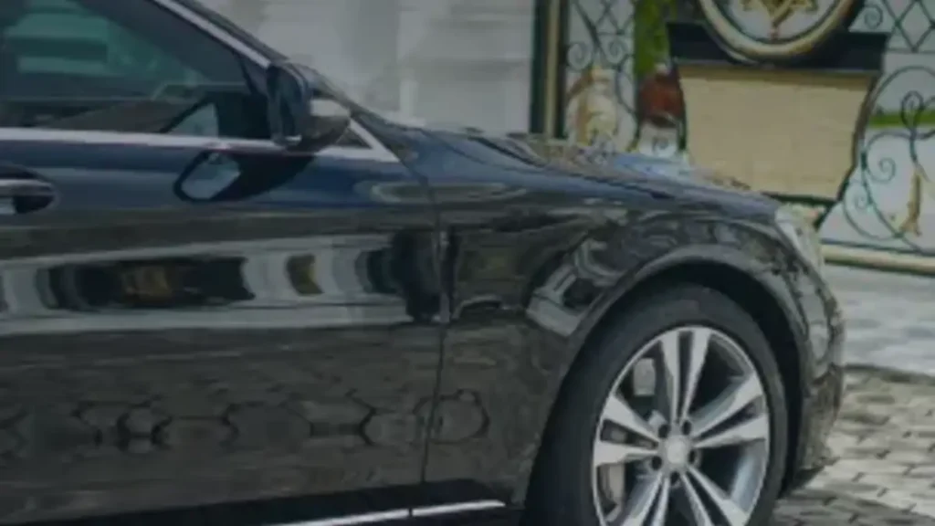 A black luxury sedan parked at a villa entrance in Bali, available for chauffeured hire