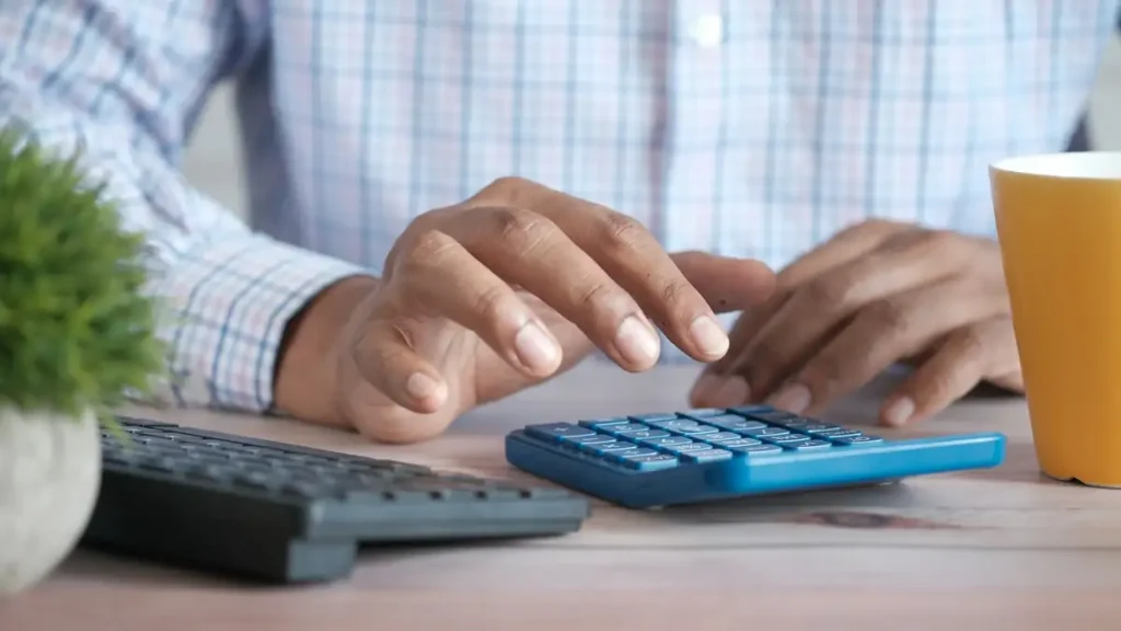 A person working at a desk with a calculator and coffee, reviewing 2027 economic trends