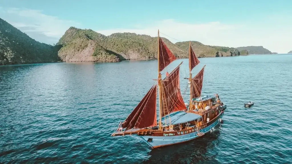 A sailing boat anchored on calm water in the Komodo archipelago, the way luxury cruises explore the park